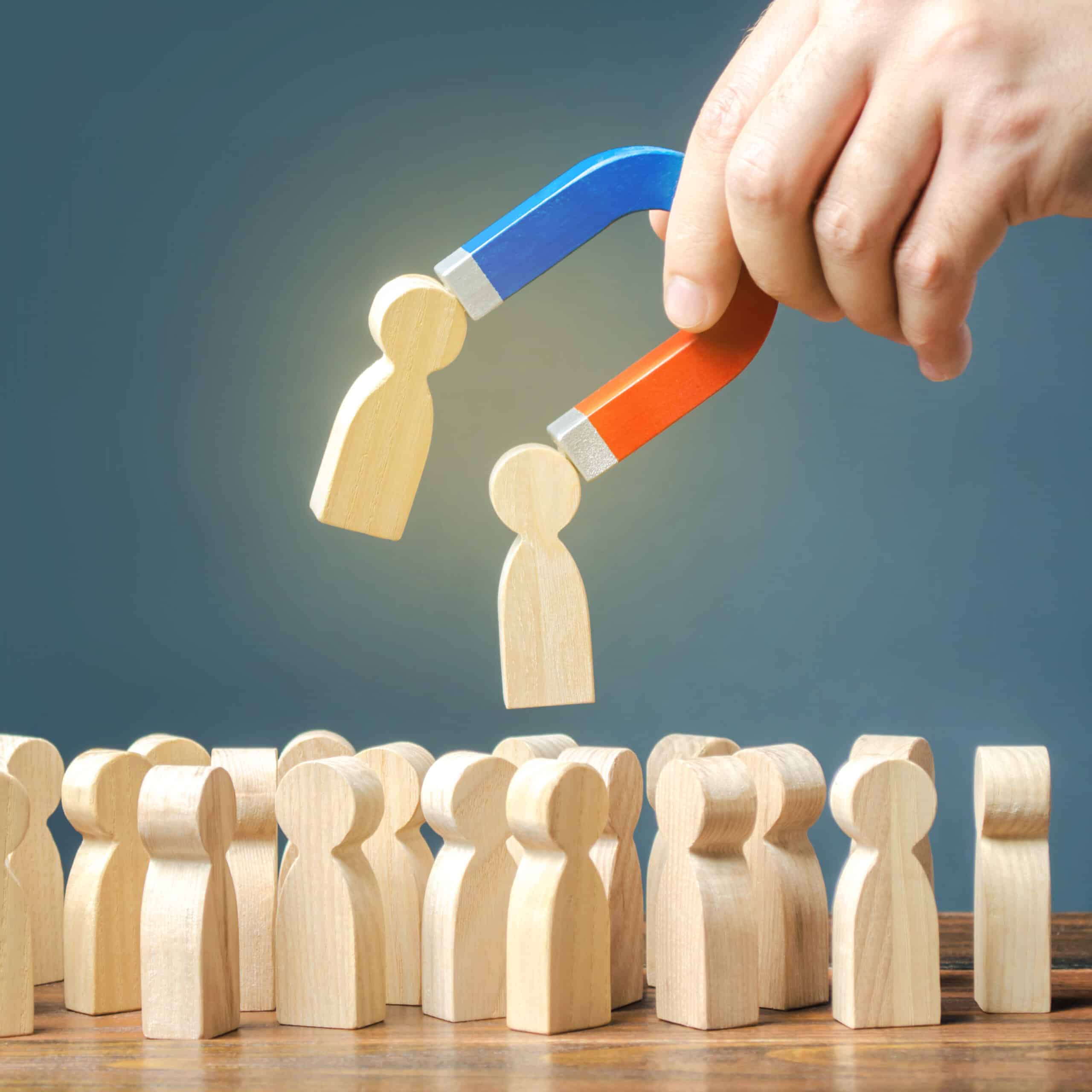 Magnet pulling wooden figures out of a crowd