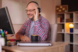 a man smiling at his computer screen whilst working from home, taking part in a remote work call