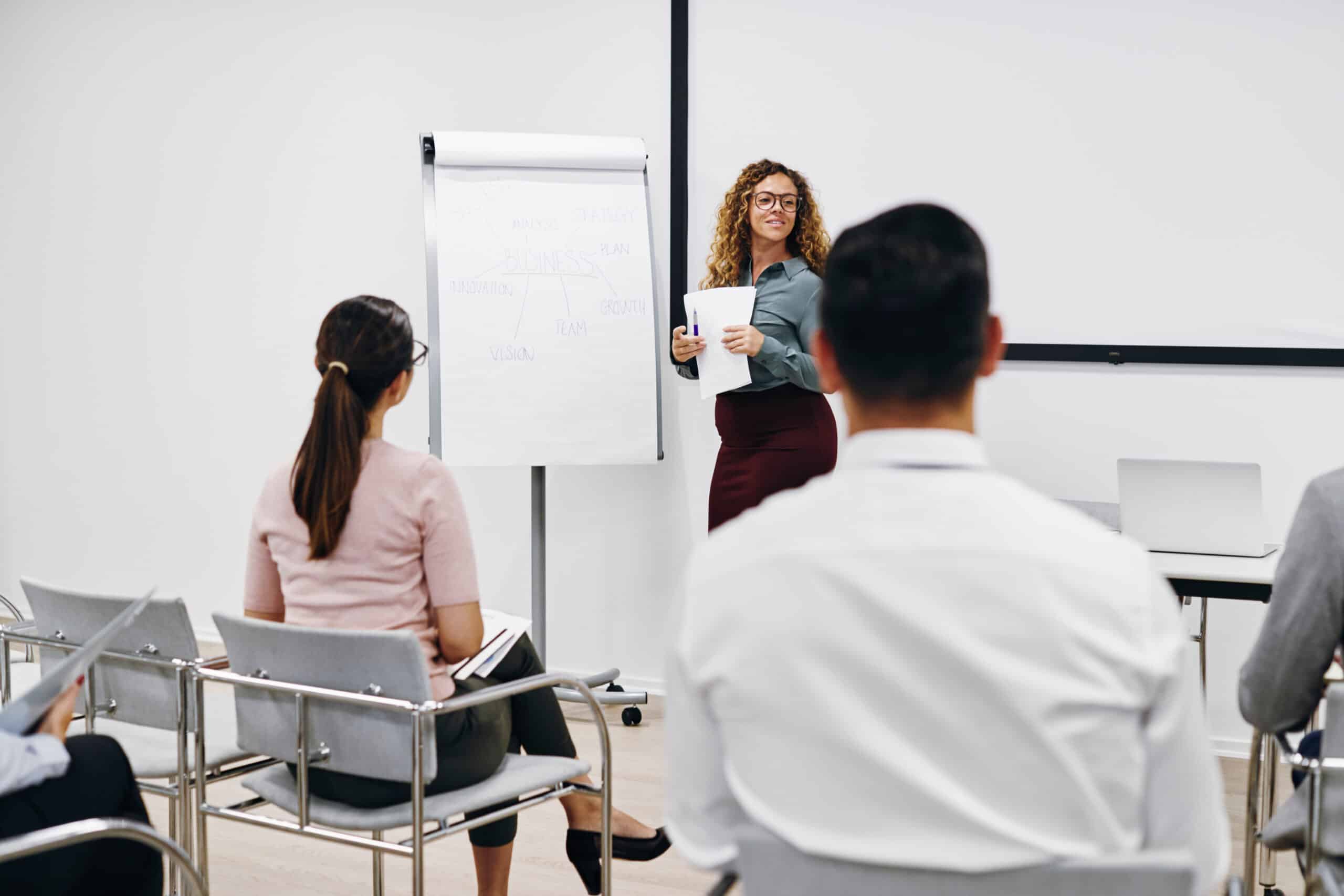 Young businesswoman giving a flip chart presentation to a group of a colleagues in the seminar room of an office