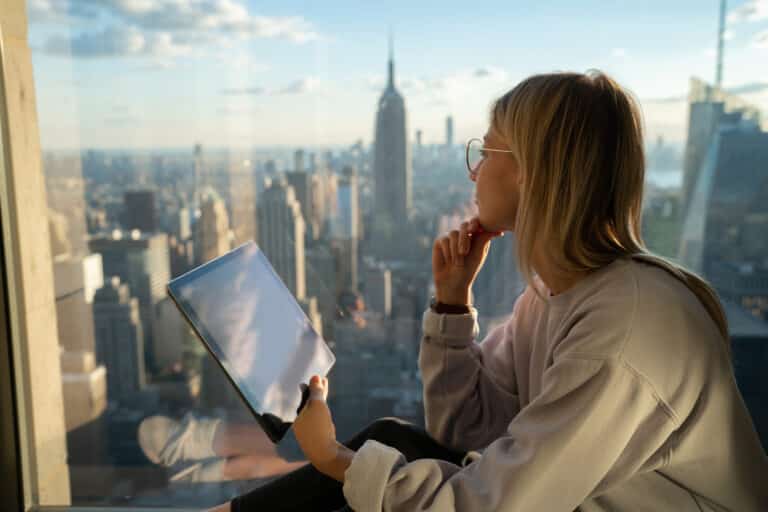 Thoughtful female digital remote worker looking into the distance, seeing a city skyline